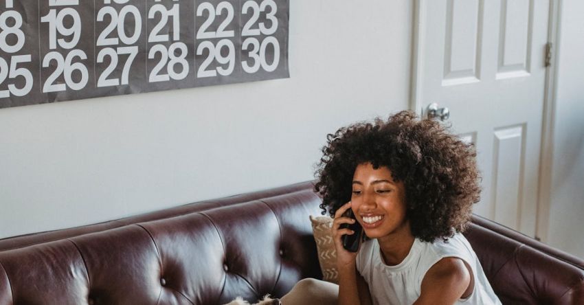 Content Calendar - Cheerful black woman speaking on smartphone while caressing dog indoors